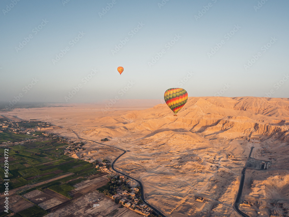 Aerial view of the agricultural fields, Luxor the desert and balloons from a hot air balloon during sunrise.