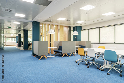 A coworking office with a boardroom table and meeting booths, wooden latticework and blue carpeted floors