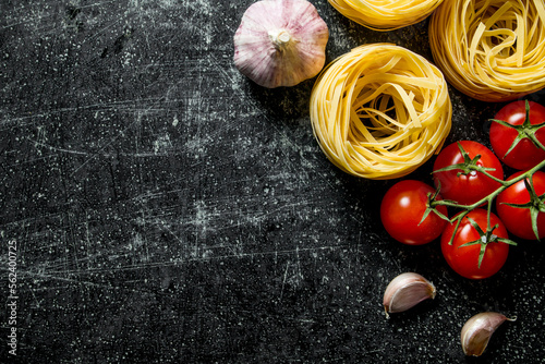 Raw tagliatelle paste with garlic and tomatoes.