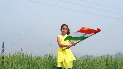 Cute indian little girl waving national tricolor flag at agriculture field.