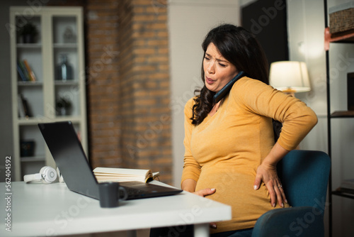 Young pregnant woman having painful contraction. Businesswoman holding her belly.