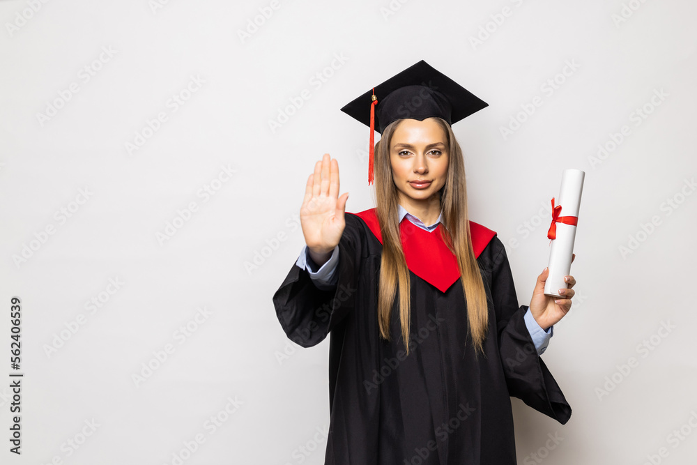 Beautiful young woman college graduate portrait wearing cap and gown with diploma isolated on white background Beautiful young woman college graduate portrait wearing cap and gown with diploma isolated on white background
