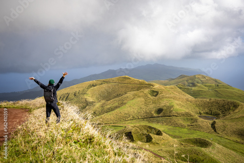 Happy woman with raised arms enjoying the views of the central highlands on São Jorge island, Azores photo