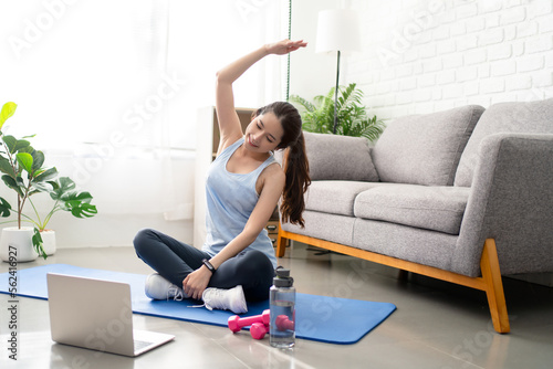 Sporty young Asian woman warming up, stretching before workout at home. Sport, fitness and healthy lifestyle concept.