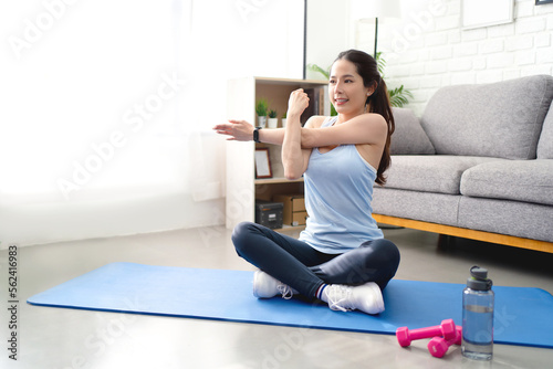 Asian woman stretching her shoulders in yoga and exercise at home during COVID-19.