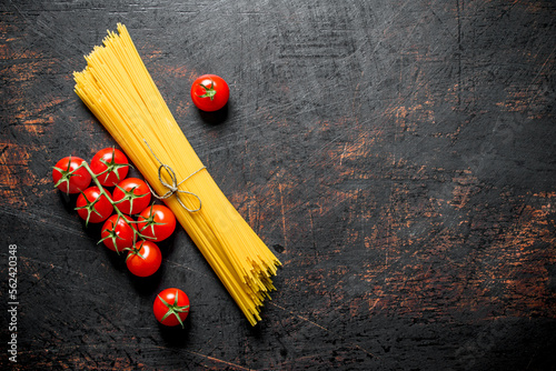 Raw spaghetti with tomatoes on a branch.