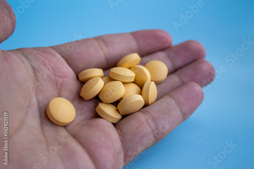 Hand holding yellow pills	