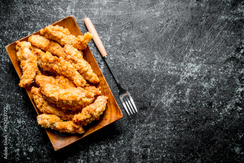 Chicken strips on a plate with a fork.