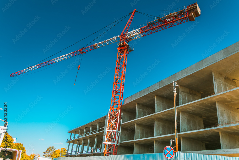 Construction crane at a construction site in the city against the blue sky. The concept of building a new area. Construction of a new building.