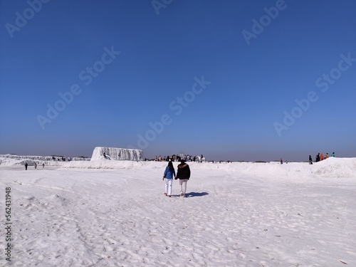 Picture of panoramic view of snow covered field with people standing in background with blue sky shot during daylight. Ice desert © abhinavmathurindia