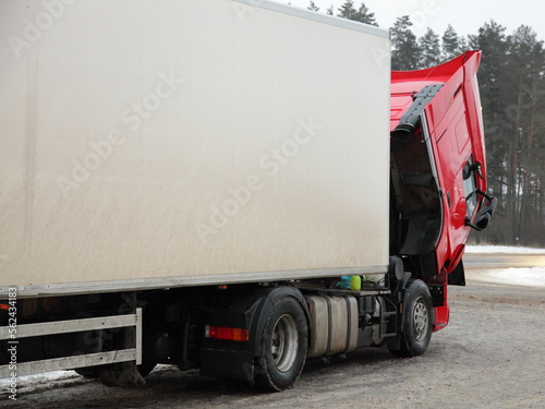 Obraz na płótnie Heavy red semi truck diesel engine repair under hood at cold winter snowy suburban road on forest background w salonie