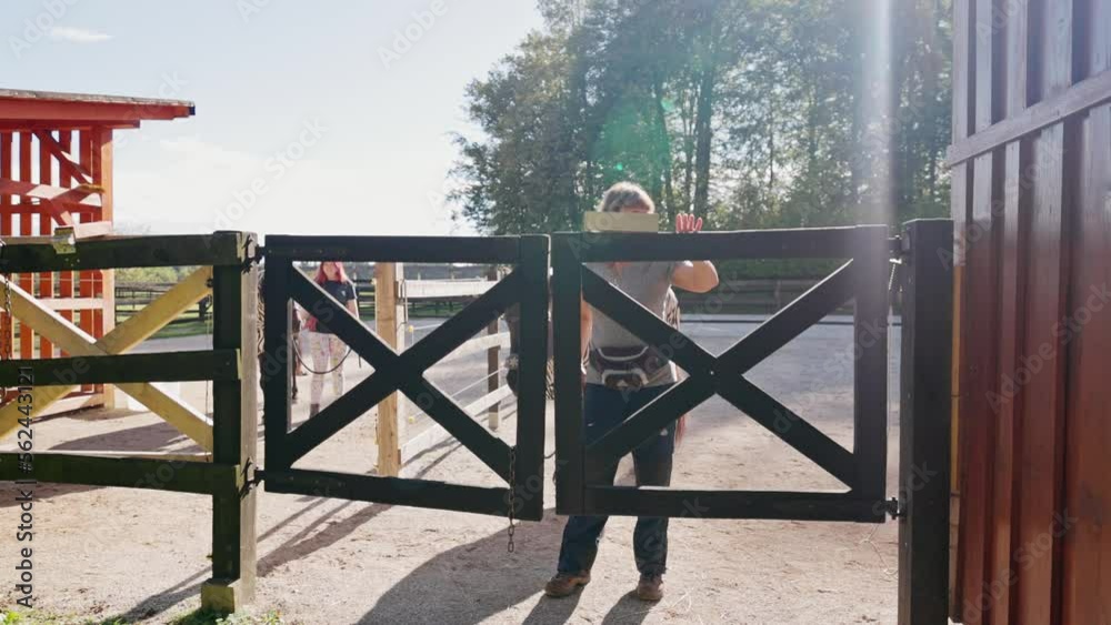 Woman opening the fence letting the horse trough - Life on the ranch Woman opening the fence letting the horse trough - Life on the ranch
