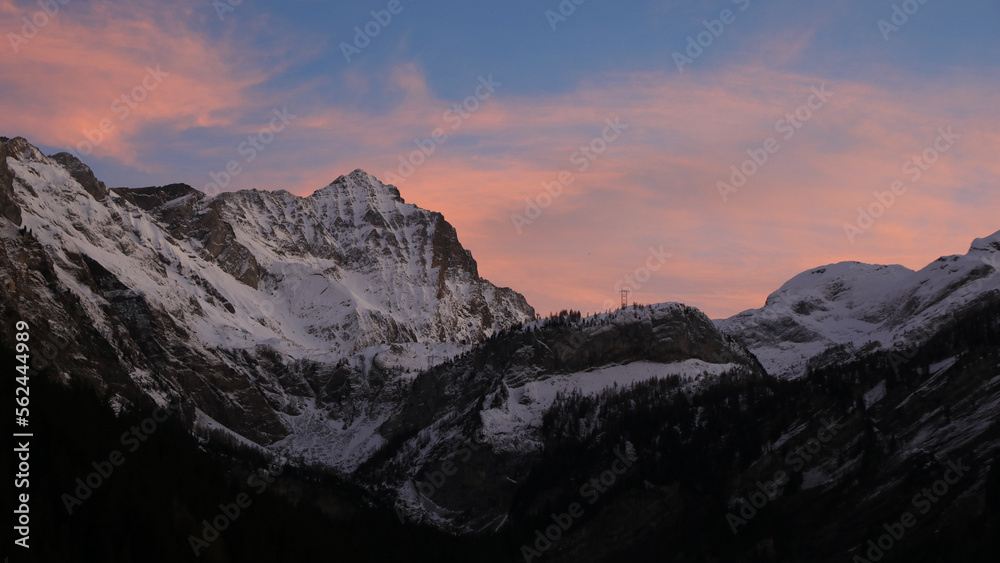 Sunlit pink clouds over Mount Arpelistock in winter.