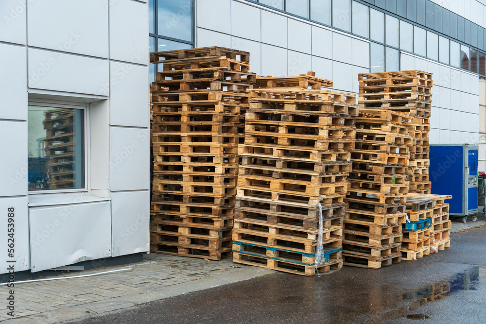 A stack of wooden pallets in an internal warehouse. An outdoor pallet storage area under the roof next to the store. Piles of Euro-type cargo pallets at a waste recycling facility. A stack of wooden pallets in an internal warehouse. An outdoor pallet storage area under the roof next to the store. Piles of Euro-type cargo pallets at a waste recycling facility.