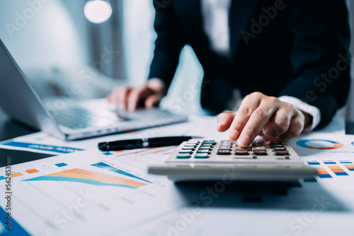 Businesswomen or Accountants use a calculator to work with financial statements and analyze company financial reports. investment, balance sheets, taxes, planning and business strategies concept. photo