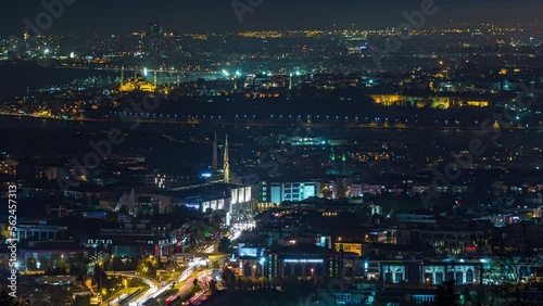 Istanbul night skyline scenery timelapse, view over Bosporus channel from Camlica hill. Marmara University Vocational School of Theology. Blue water of Bosporus channel with ship. Traffic on roads photo