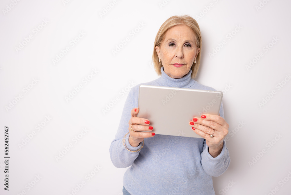 Portrait of smiling beautiful senior aged mature woman using tablet computer, isolated over white background. Copy space for text. Portrait of smiling beautiful senior aged mature woman using tablet computer, isolated over white background. Copy space for text.