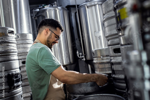 Man working in craft brewery examining production of the beer.