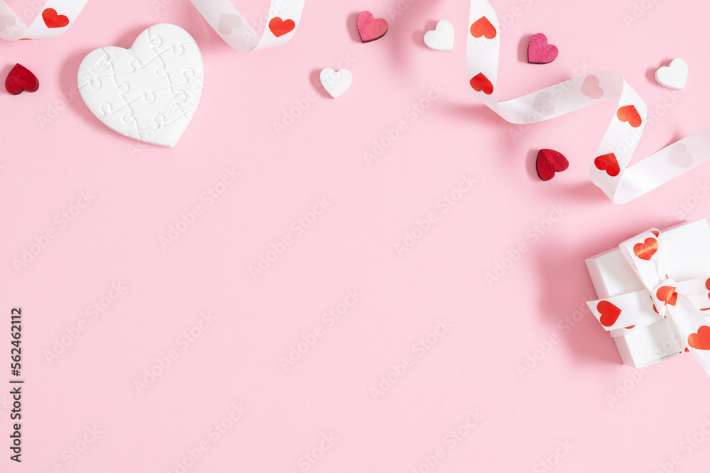 Valentine's Day background. White cute confetti hearts, gift box ribbon bow curly ribbon with hearts on isolated pastel pink background. Valentine's day concept. Flat lay, top view, copy space
