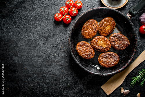 Cutlets in the pan with a wooden spatula and cherry.