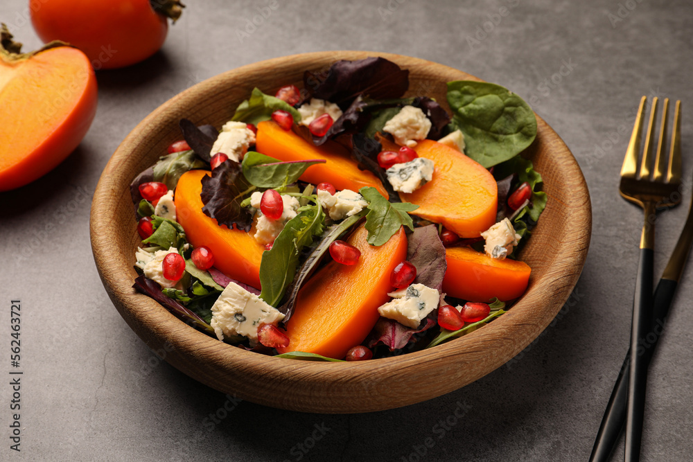 Delicious persimmon salad with cheese and pomegranate served on grey table