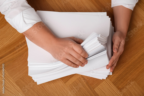Man stacking documents at wooden table, top view