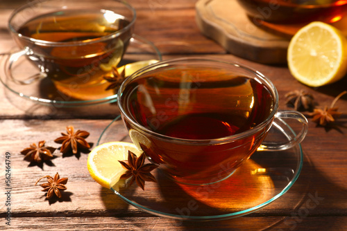 Aromatic tea with anise stars and lemon on wooden table, closeup
