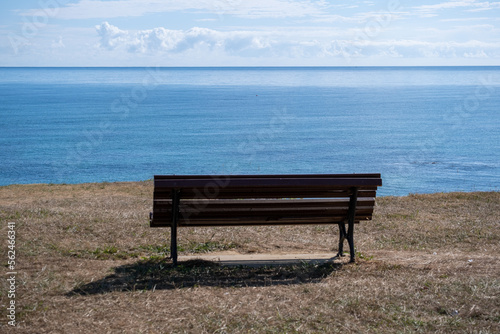 Old brown bench having a view over the sea.