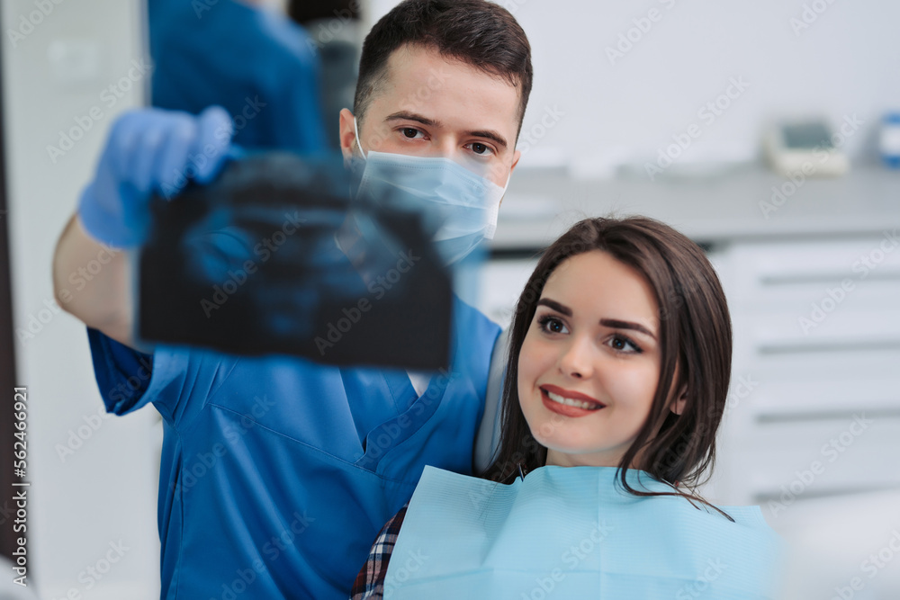 Male dentist showing x-ray to his patient in dental clinic Male dentist showing x-ray to his patient in dental clinic
