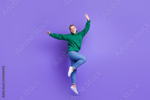 Full length photo of excited dreamy lady wear green sweater rising hands arms jumping high isolated violet color background