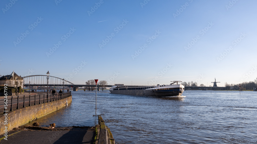 Empty barge sails downstream during high tide of the river IJssel past the Hanseatic city of Deventer in the Netherlands