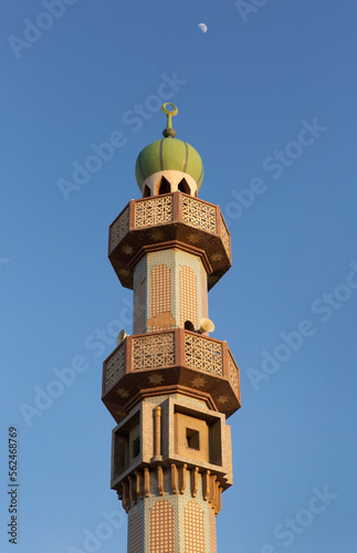 Minaret of Aali grand mosque in the evening with moon at the backdrop
