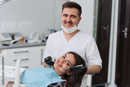 Dental surgeon and patient smiling happy after dental checkup  looking at camera.
