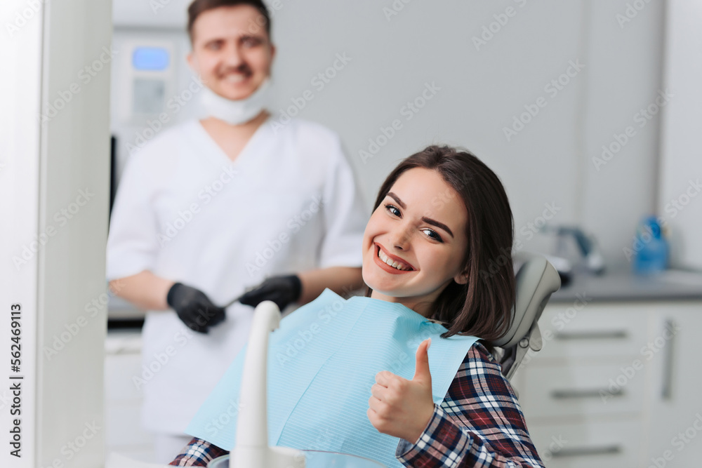 Obraz premium Happy young woman and male dentist after treatment in clinic