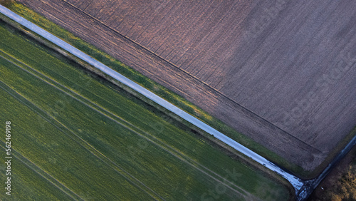 Geometric agricultural fields showing green meadow and plowed fields taken by drone.