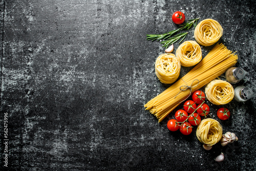 Raw tagliatelle and spaghetti with spices, tomatoes and rosemary.