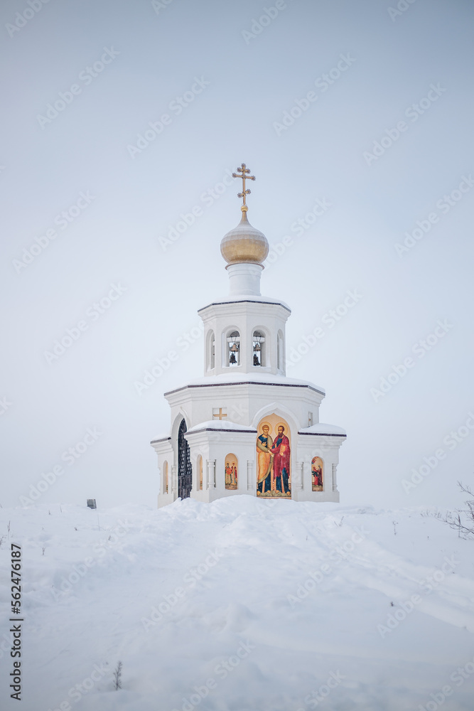 Fototapeta premium The church stands alone on a hill in the snow