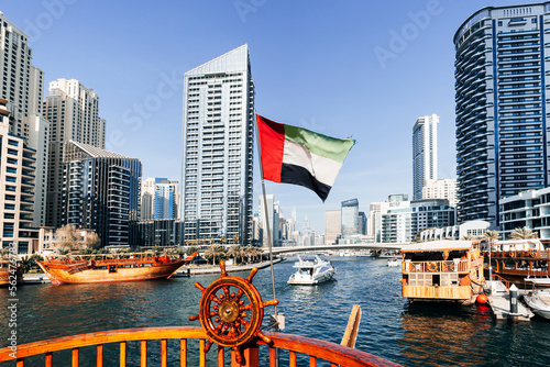 Photography view from a boat in sea to the flag of the United Arab Emirates and the cityscape with the tower
