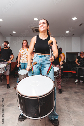 A girl plays the drum in a batucada class with a smiling attitude photo