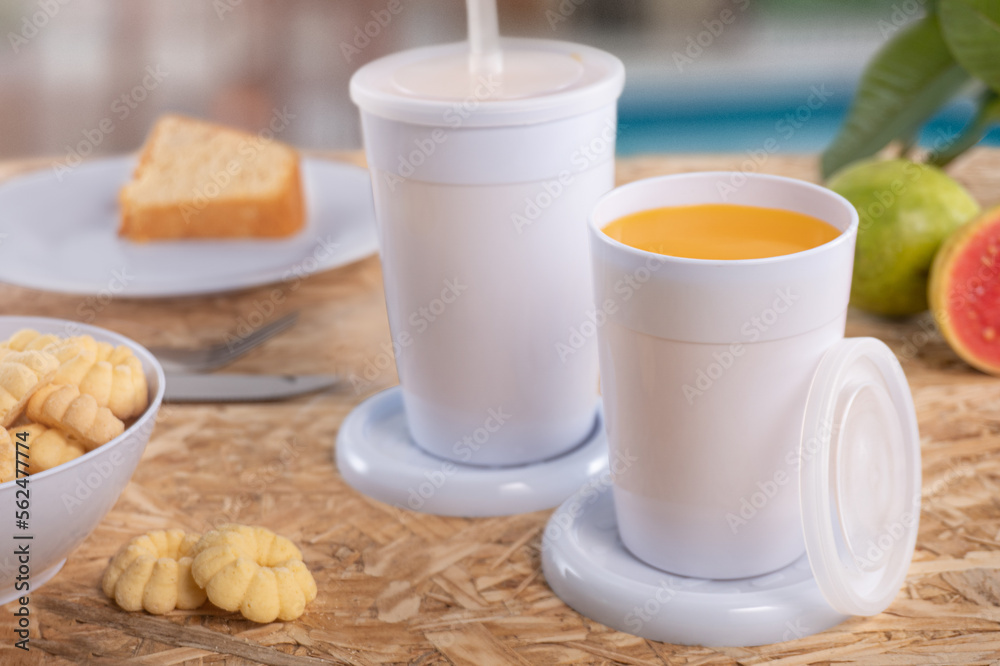 Breakfast table with juice. Colorful cups and plates Breakfast table with juice. Colorful cups and plates