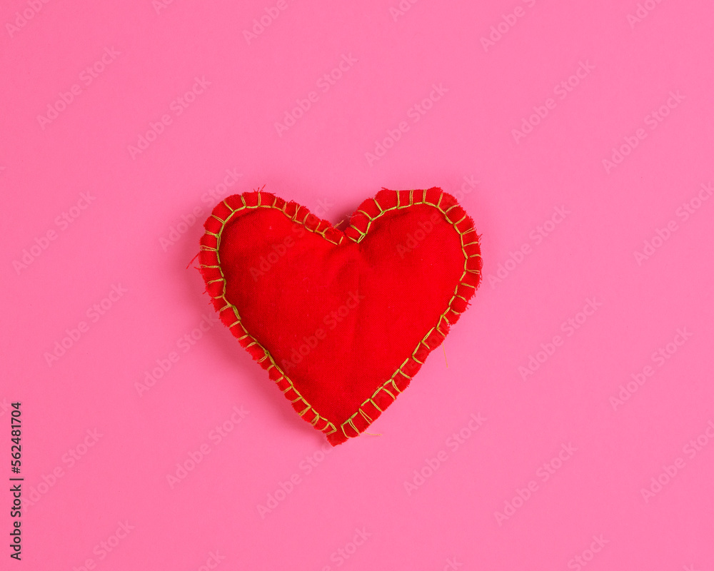 A bright red fabric heart on a magenta background. Flat lay