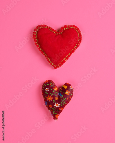 Two hearts sewn from fabric on a magenta background. Vertical arrangement. Flat lay
