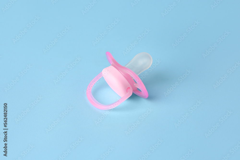 One new baby pacifier on light blue background One new baby pacifier on light blue background