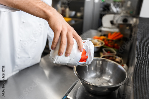 cooking food, baking and people concept - close up of male chef cook with eggs pouring flour into bowl at restaurant or bakery kitchen