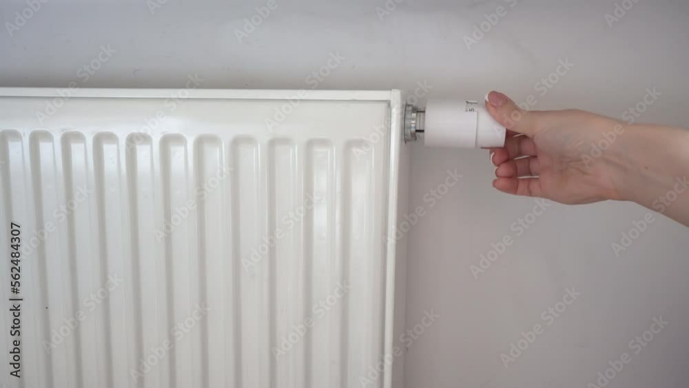 A woman turns the regulator of the thermostatic radiator valve to the hight position. Heating of the apartment in the cold season. A woman turns the regulator of the thermostatic radiator valve to the hight position. Heating of the apartment in the cold season.