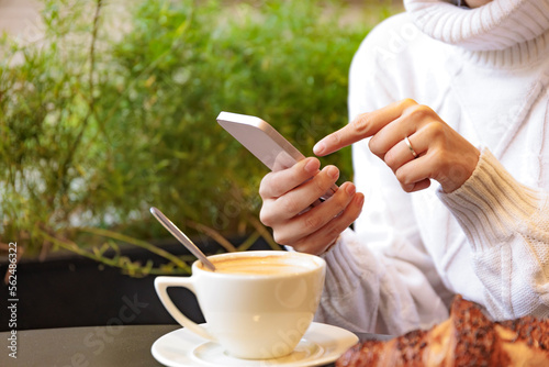 Hand's woman using cellphone while having breakfast at home