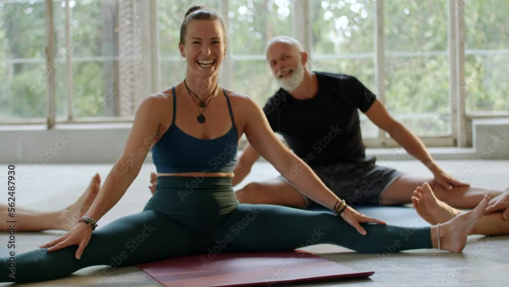 Smiling woman stretching on an exercise mat during a class in a yoga studio