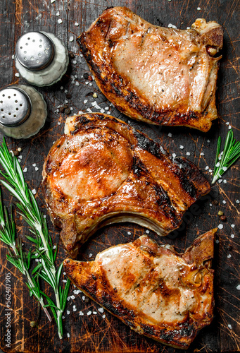 Grilled pork steaks with rosemary and salt on an old board.