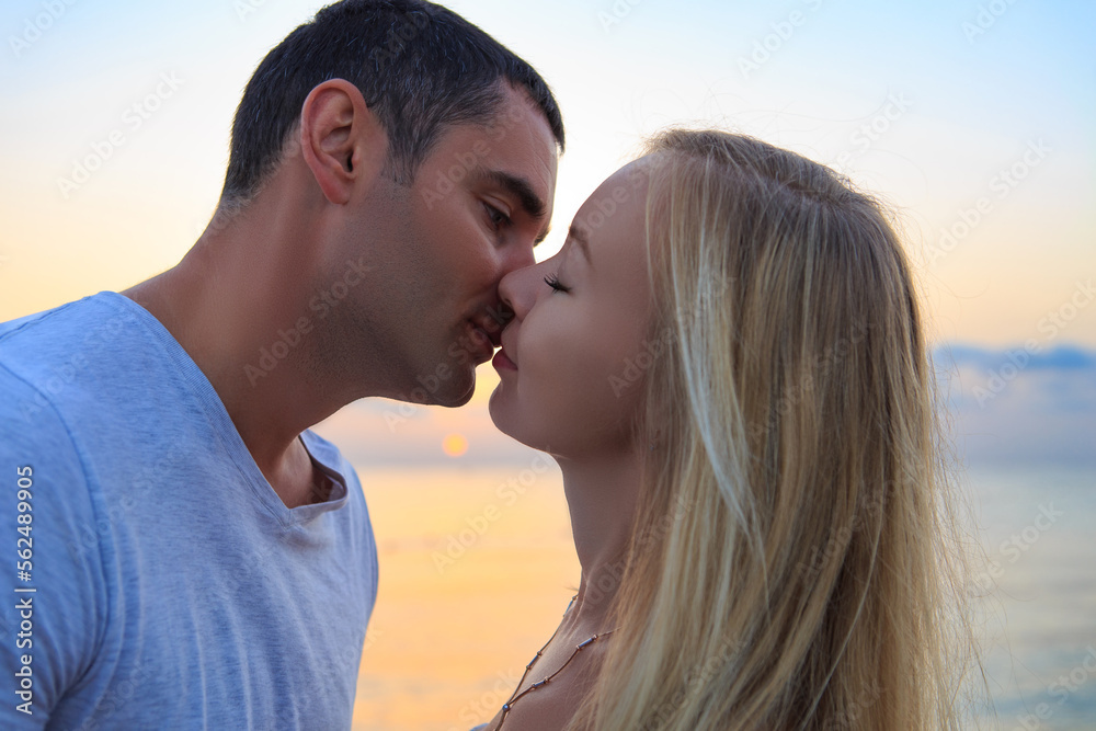 A couple of young people on the seashore in a resort area. People on the background of sunrise or sunset A couple of young people on the seashore in a resort area. People on the background of sunrise or sunset