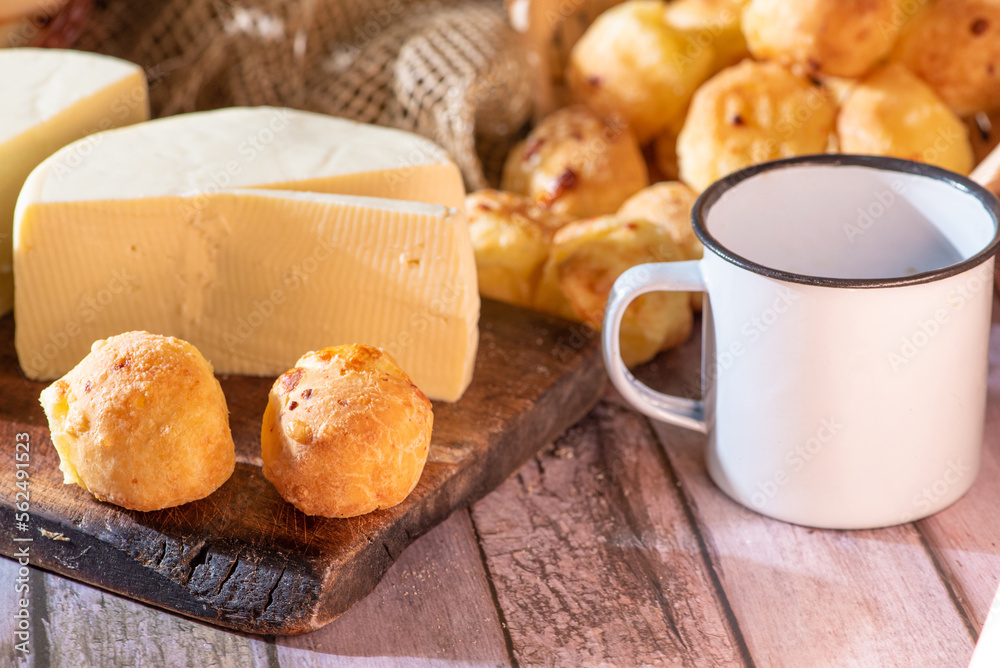 Cheese bread and more, cheese bread, manioc flour cookies and Minas cheese arranged on a rustic wooden surface with accessories, selective focus.